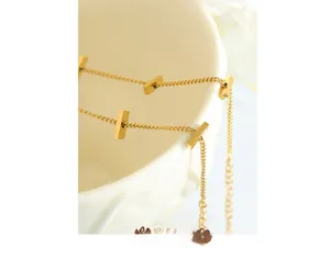 Detailed close-up of a minimalist gold bar chain bracelet on a ceramic bowl