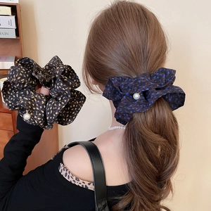 Detail of floral scrunchies with elegant pearl pendants and smooth fabric texture