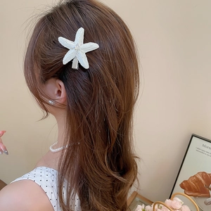 Détail de la pince à cheveux étoile de mer blanche avec diamant sur cheveux bruns