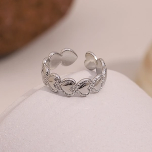 Detail of silver heart-shaped beaded open ring with textured grain edges and metal finish