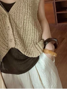 Close-up of a vintage beige knitted vest with coarse texture and irregular retro bracelet