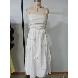Detail of white midi dress with pearl straps and 3D floral appliqués on the hem