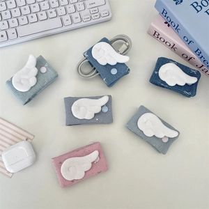 Denim fabric cable organizers with plush wings on a desk with a keyboard and books