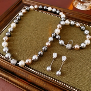 Detailed close-up of multi-colored pearl necklace and earrings on green velvet tray