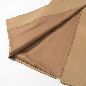 Close-up of the khaki trench coat hem showing neat stitching and dark brown inner lining