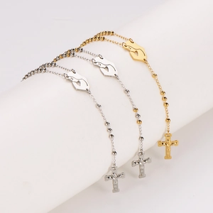 Three gold and silver rosary-style prayer necklaces with cross pendants on a white stand