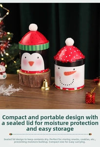 Detailed view of Christmas tin canister with festive penguin design and pom-pom lid