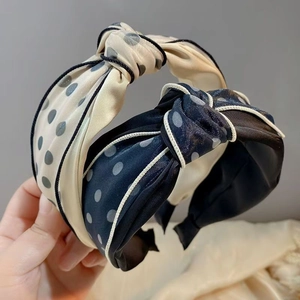 Detail of twisted fabric headband with polka dot patterns in beige and navy blue