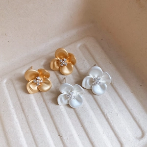 Detailed view of elegant gold and silver floral stud earrings with sparkling zircon