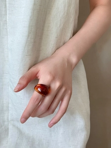 Close-up of a translucent amber resin dome ring worn on a finger with warm aesthetic