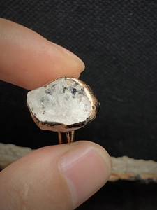 Macro view of raw birthstone crystal with copper-plated metal bezel on adjustable ring