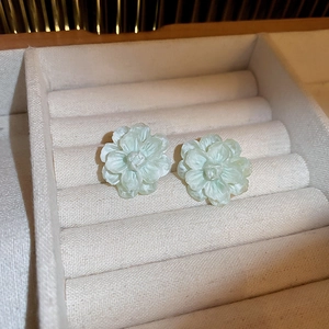 Elegant mint green acrylic flower stud earrings with carved petals in a beige velvet box