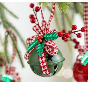 Detailed macro view of green Christmas bell with red ribbon and holly on a tree