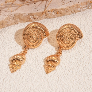 Detailed view of gold shell earrings with spiral conch texture on natural stone