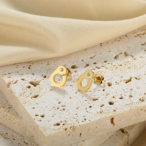 Macro shot of gold handcuff stud earrings with zircon on premium stone and silk