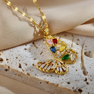 Collier papillon doré avec zircons colorés, vue à 45 degrés sur un fond de tissu soyeux