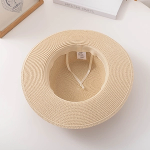 Detail of beige paper straw hat showing interior adjustable strap and size label
