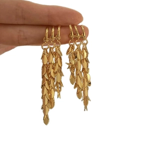 Elegant gold wheat tassel earrings in layered metal design held against white background