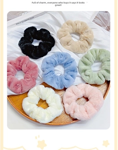 Close-up of seven assorted plush hair scrunchies in a wooden tray with silk background