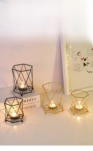 Detail of geometric iron candle holder with gold and black frames and glass cup