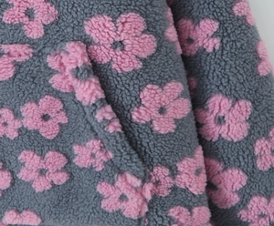 Detail of grey sherpa fleece fabric featuring pink floral prints and durable pocket stitching