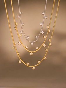 Détail de chaînes serpent en or et argent avec pendentifs en zircons ronds brillants