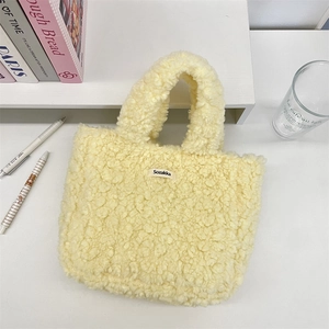 Close-up of soft yellow plush tote bag with Sozakka label on a minimal white desk