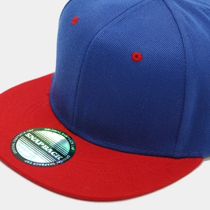 Dettaglio del cappellino snapback bicolore con corona blu navy e visiera rossa