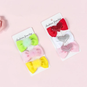 Detail view of colorful bow hair clips with pom-poms and glitter hearts for children