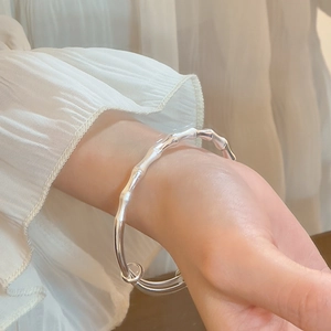 Gros plan d'un bracelet en argent forme bambou avec finition mate sur fond en tissu doux