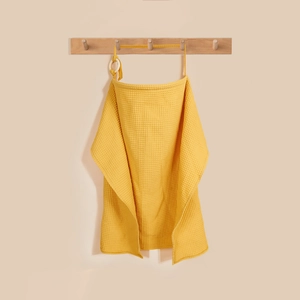 Close-up of ginger waffle cotton nursing cover with adjustable strap on wooden hook