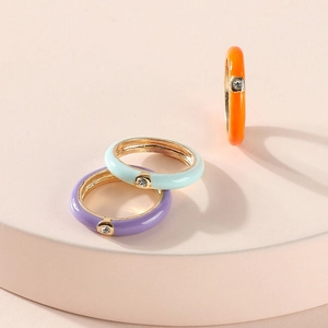 Macro shot of colorful enamel rings with cubic zirconia on elegant pink podiums