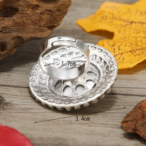 Top view of vintage silver round ring with radial patterns on a textured wood surface