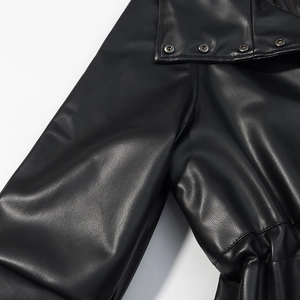 Vue détaillée d'une veste en simili cuir noir avec boutons-pression métalliques et texture fine