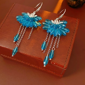 Gros plan macro de boucles d'oreilles fleur en cristal bleu avec franges sur une boîte en cuir