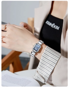 Close-up of elegant silver quartz watch with faceted navy blue rectangular dial on wrist