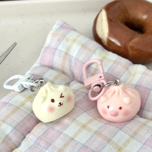 Detailed close-up of cute steamed bun keychains in white and pink on a plaid cushion