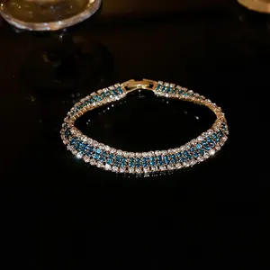 Elegant three-row gold bracelet with alternating blue and white crystals in luxury design