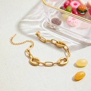 Gros plan d'un bracelet à maillons dorés avec extension sur un fond de sable