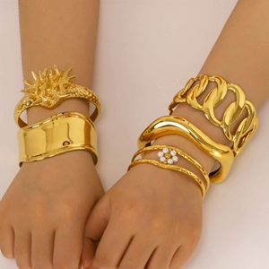 Stack of gold geometric 18K plated stainless steel bangles with spikes and pearl detail