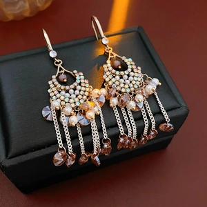 Detail of gold drop earrings with zircon crystals, pearls and elegant metal tassels