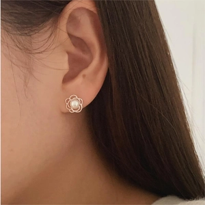 Macro view of floral pearl earrings featuring gold petals on a model's ear