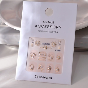 Detail of 3D nail art stickers with faux pearls and gold studs on retail packaging card
