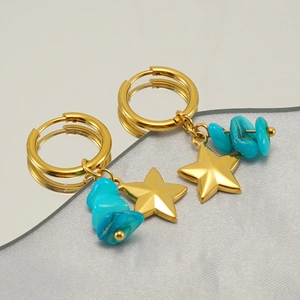 Macro detail of gold star earrings featuring natural turquoise stones on a mirror surface