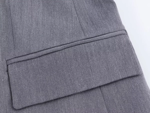 Détail de la poche de costume gris foncé montrant des coutures précises et la texture sergée