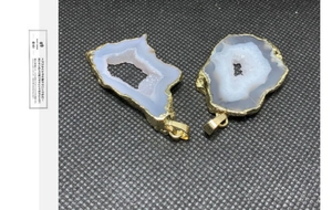 Dettaglio del ciondolo in geode di agata naturale con bordi placcati in oro 14K su fondo nero