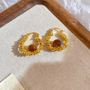 Close-up of vintage golden hoop earrings with textured metal and brown resin beads