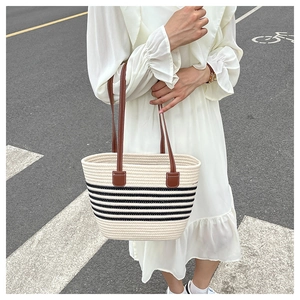 Scatto lifestyle di una borsa tote intrecciata a righe con manici in pelle marrone