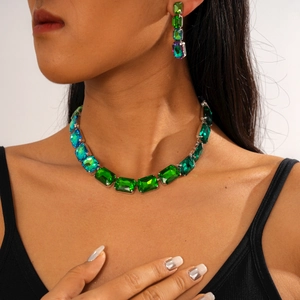 Close-up of green crystal geometric necklace and earrings set on a female model