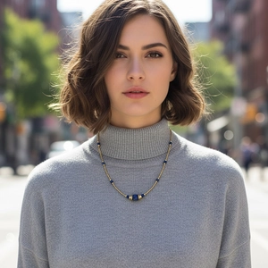 Close-up of gold chain necklace with blue lapis lazuli beads on grey turtleneck